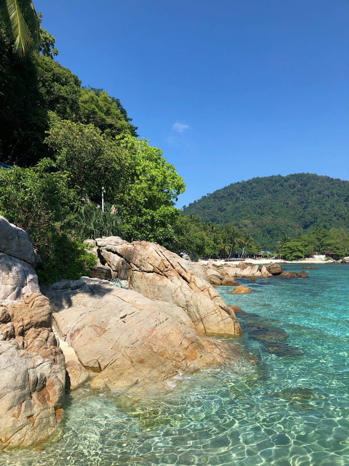Rocky shoreline with crystal-clear turquoise water at Perhentian Islands, Terengganu, Malaysia