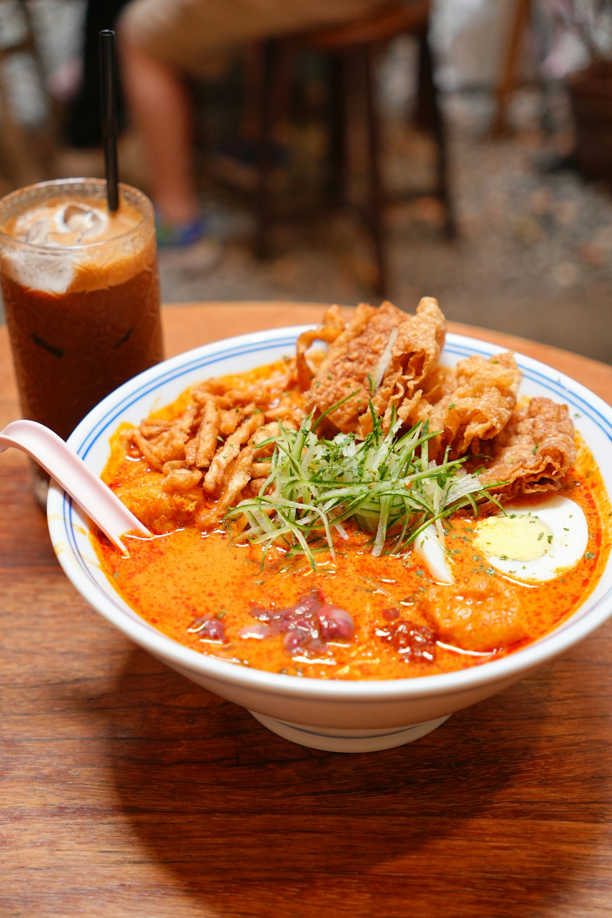 Rich Nyonya laksa bowl with egg, fried toppings and iced coffee, Malacca, Malaysia