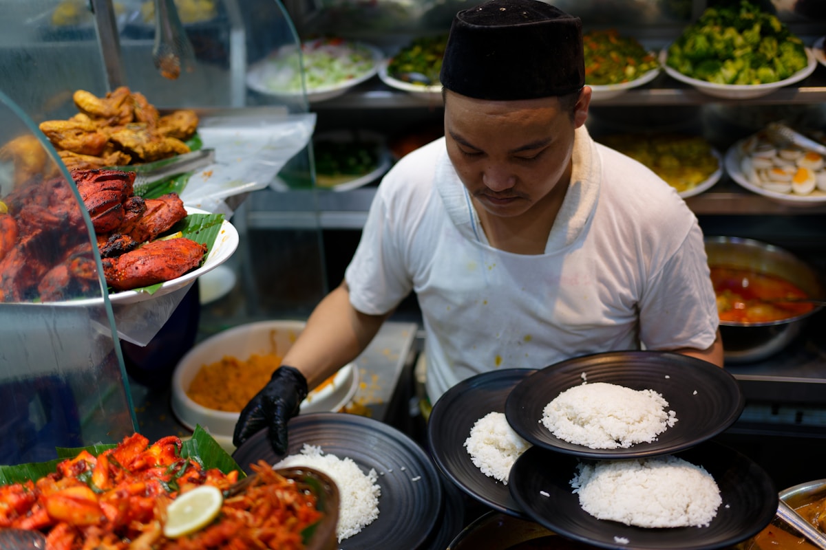 Hawker at nasi kandar stall serving rice plates at George Town, Penang, Malaysia