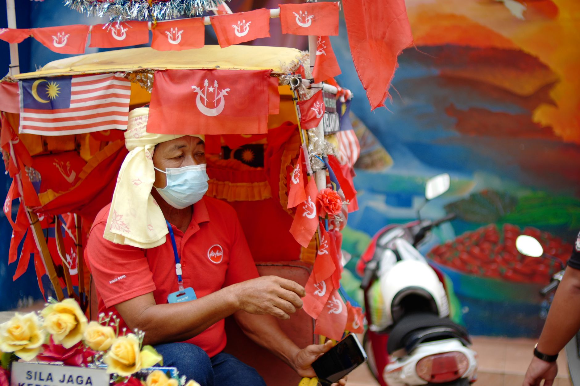 Trishaw driver with traditional decorated rickshaw bearing Malaysian and Kelantan state flags, Kota Bharu, Malaysia