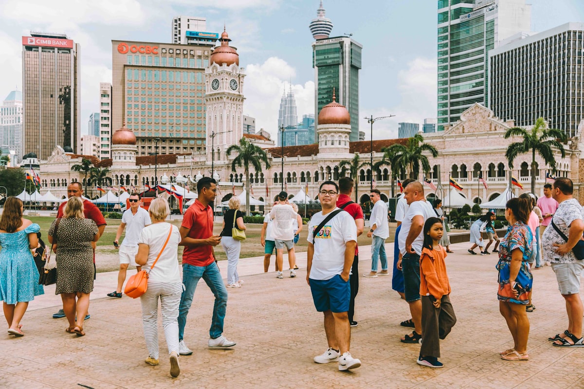 Tourists at Merdeka Square in Kuala Lumpur with Sultan Abdul Samad Building and city skyline