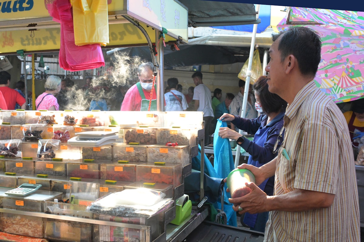 Bowl of Penang asam laksa with thick noodles, herbs, and prawn paste on a hawker table