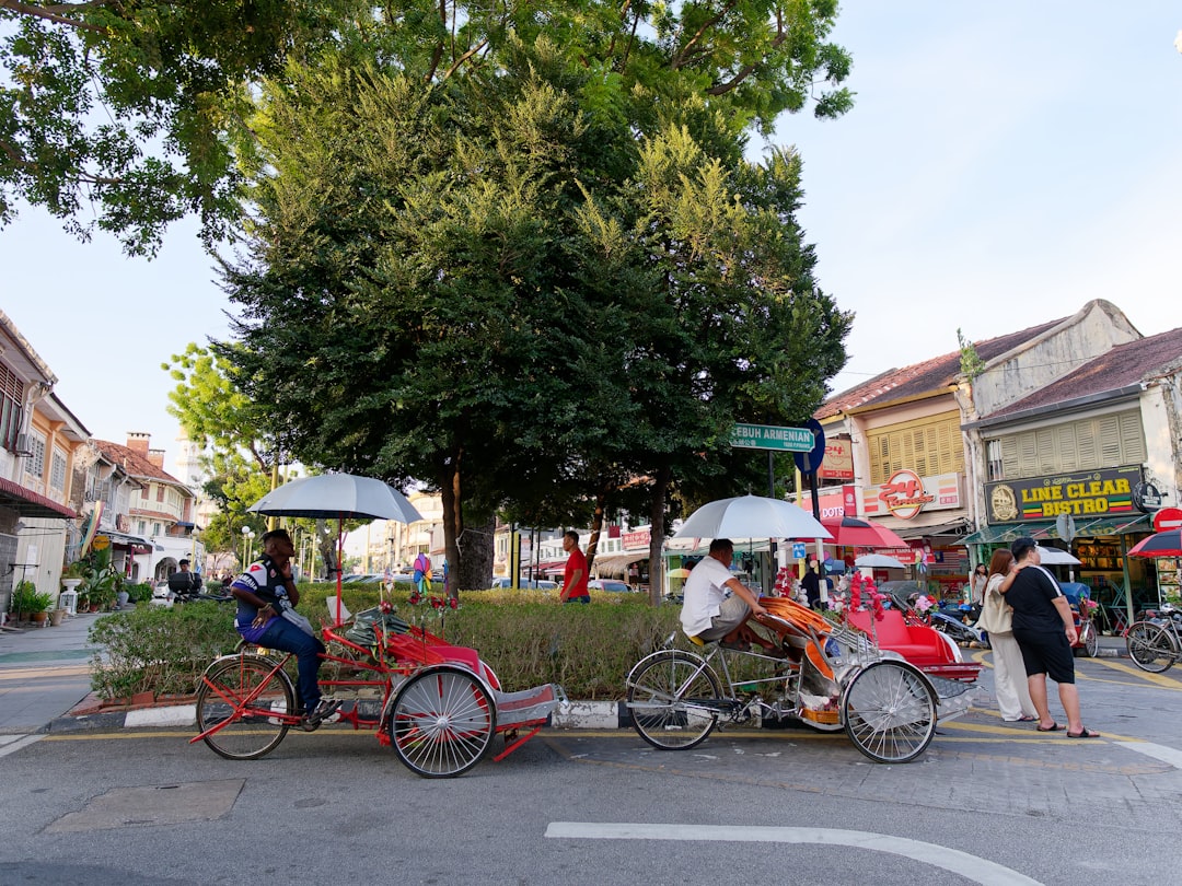Colourful trishaws parked on a street in George Town, Penang, with heritage shophouses in the background