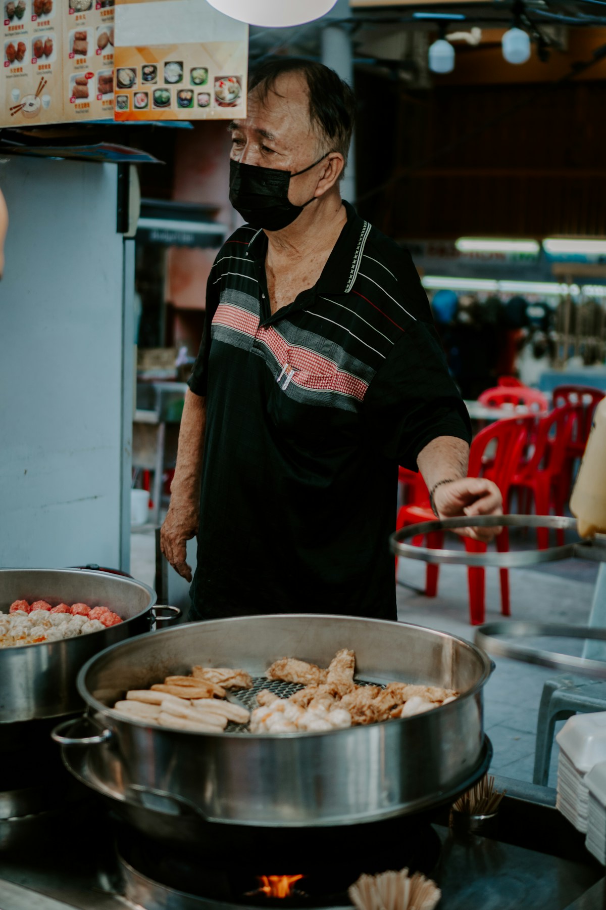 Hawker cooking over a flaming wok at a Penang street food stall at night