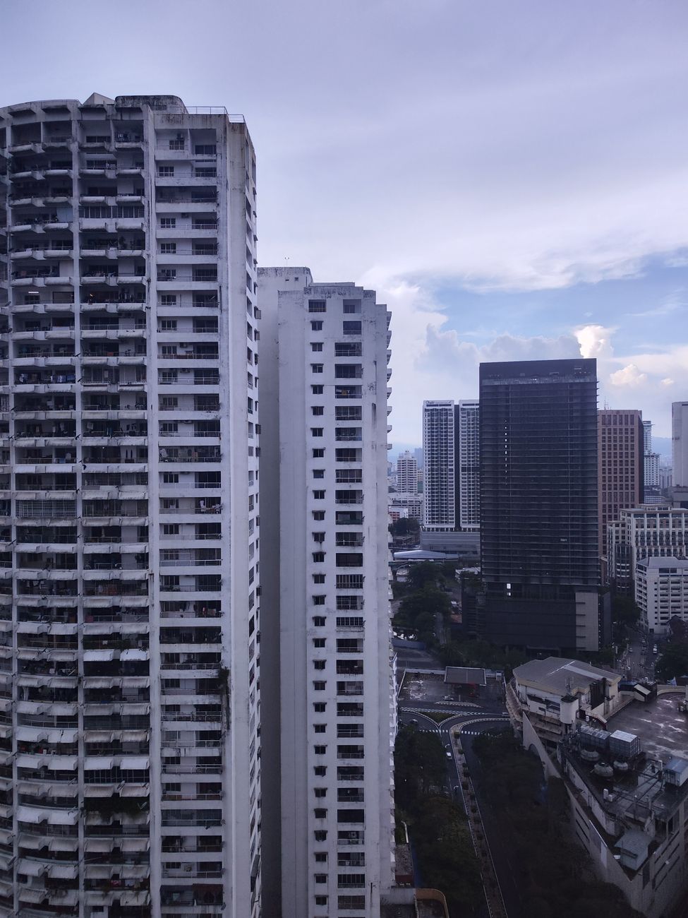 Kuala Lumpur city skyline with the Petronas Twin Towers rising above a dense urban canopy on a clear afternoon