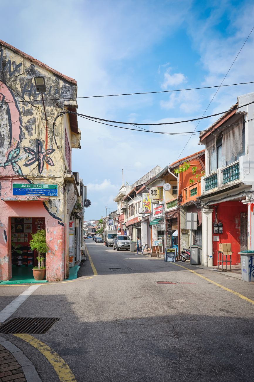 Colourful heritage shophouse facades lining a quiet street in Georgetown, Penang, with traditional five-foot walkways in afternoon light
